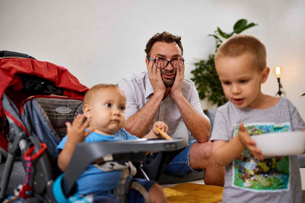 Père fatigué entouré de ses jeunes enfants